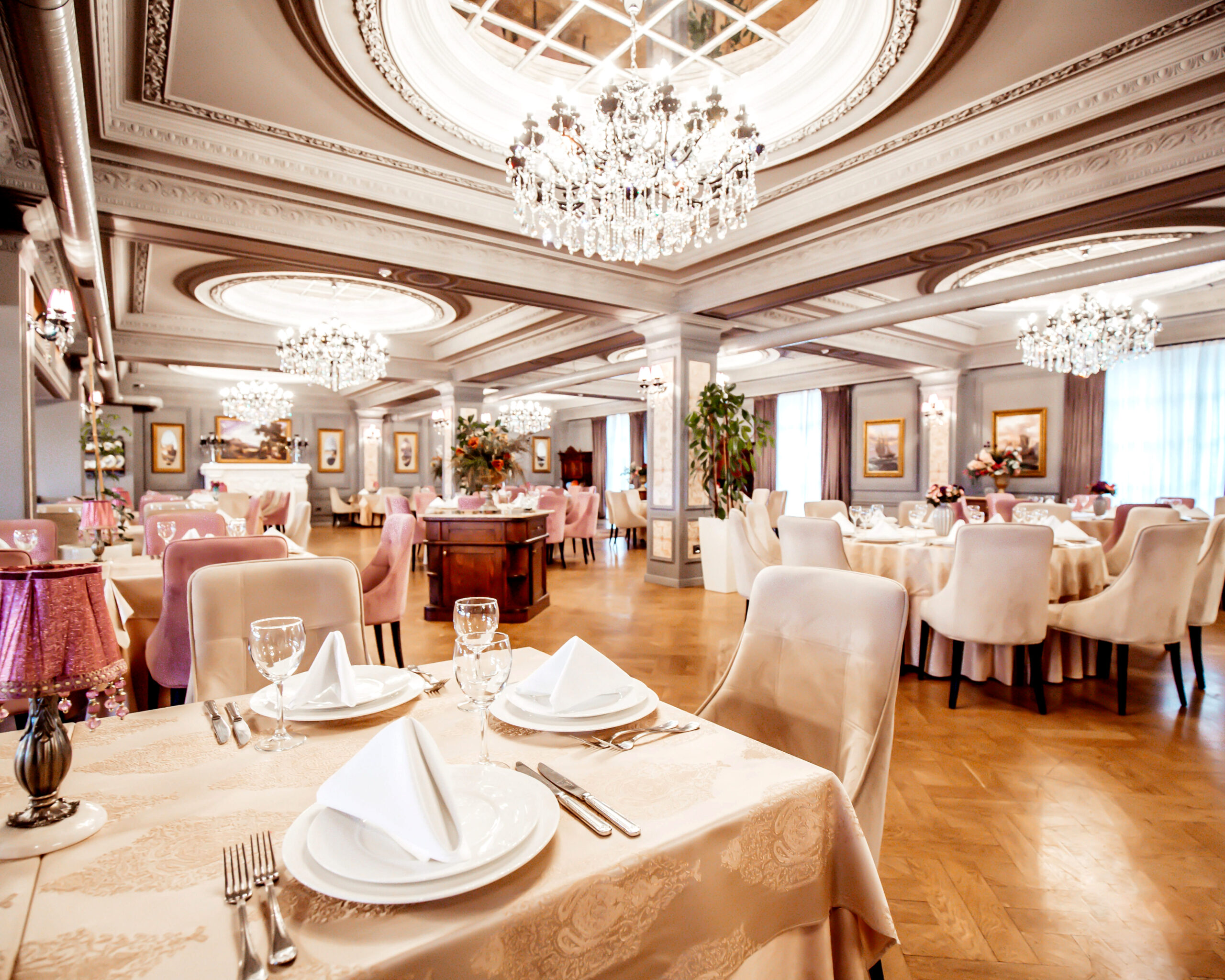 restaurant hall with round and square tables some chairs and plants