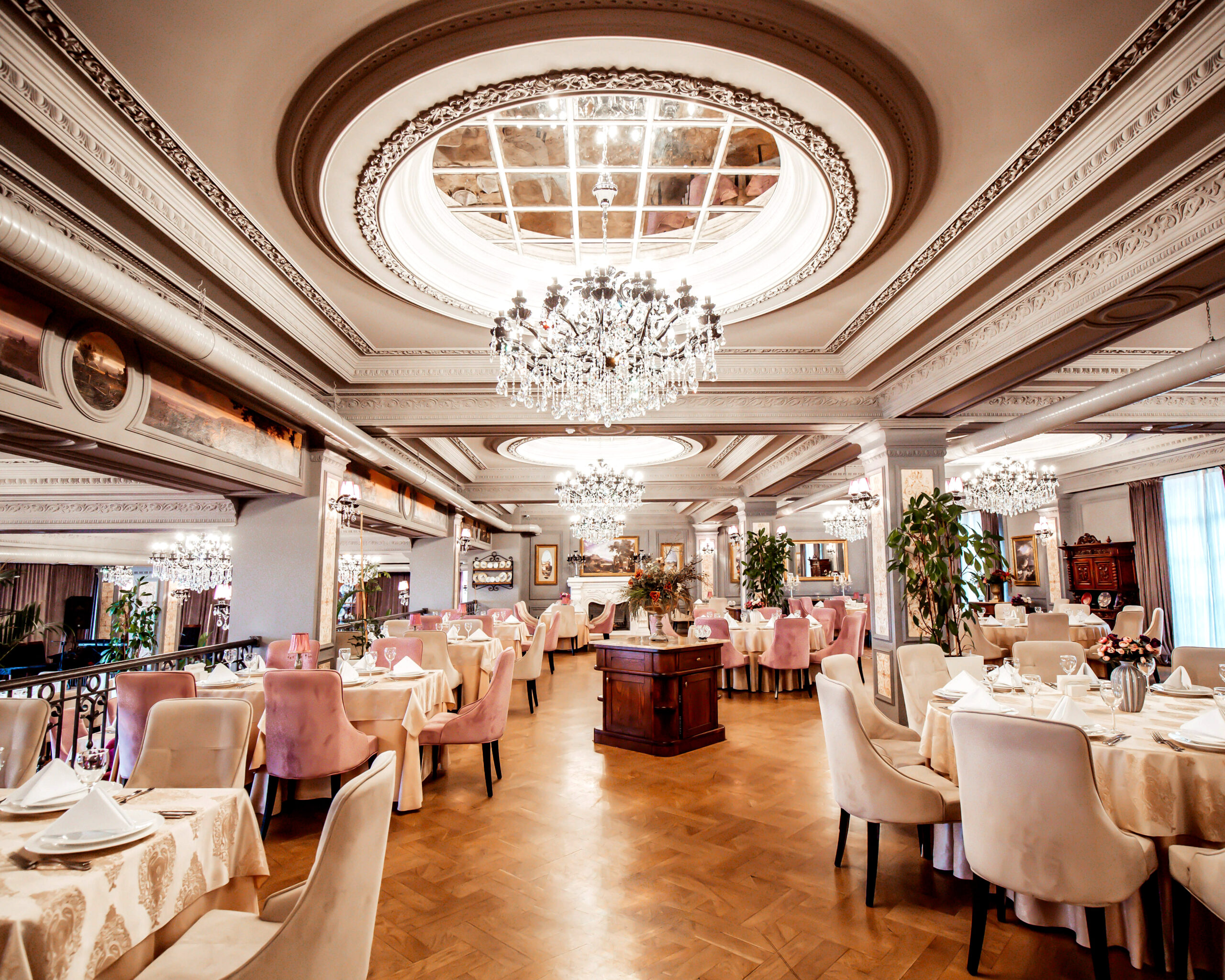 restaurant hall with round and square tables some chairs and plants