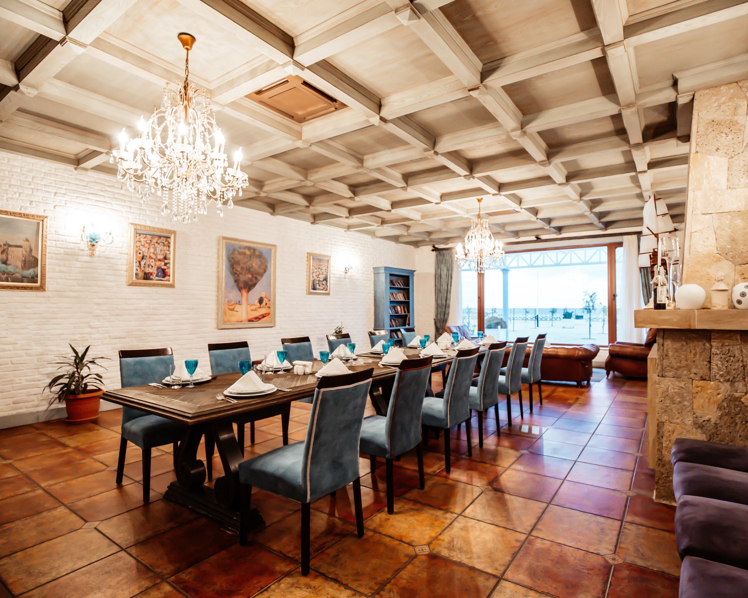 restaurant private room with table for 12 blue chairs white brick walls wide window and paintings